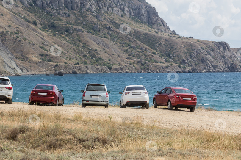 Скачать Машины у залива на берегу моря перед горами. фотосток Ozero