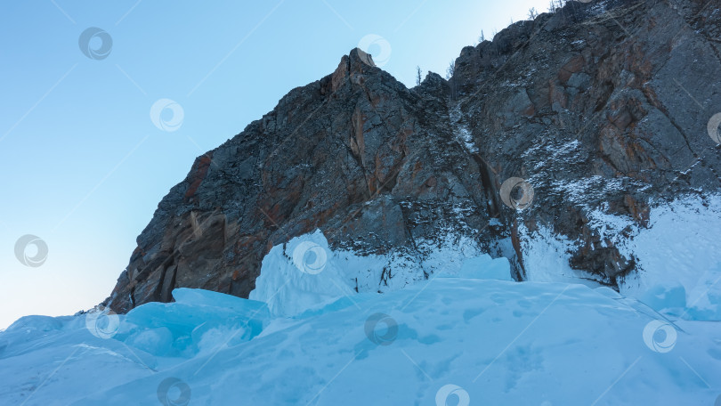 Скачать Живописная гранитная скала на фоне голубого неба. Трещины на каменных склонах. фотосток Ozero