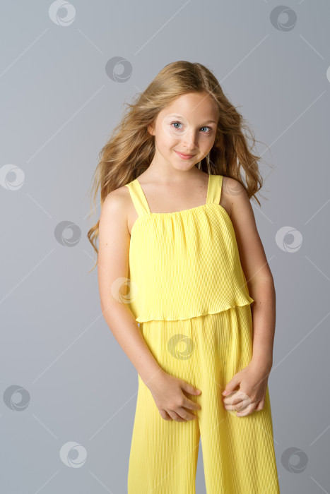 Скачать красивая девушка с длинными волосами в желтом позирует на белом фоне. фотосток Ozero
