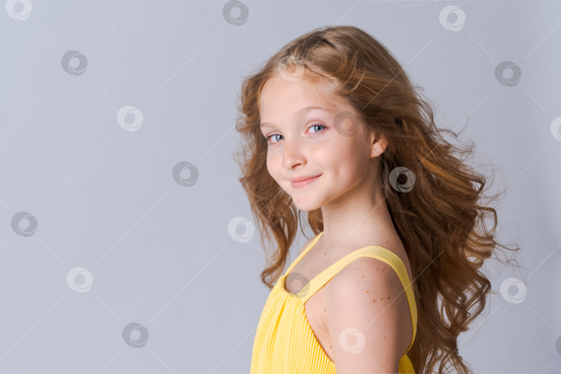 Скачать Портрет счастливой девочки школьного возраста в полный рост в желтой одежде с длинными волнистыми фотосток Ozero