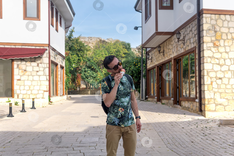 Скачать турист ест мороженое на улице средиземноморского городка фотосток Ozero