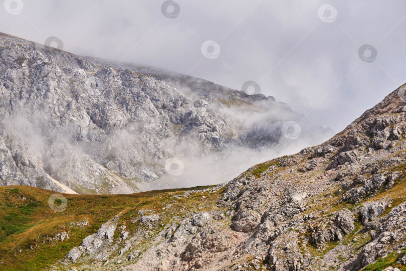 Скачать скалистый горный пейзаж с облаками, поднимающимися из ущелья фотосток Ozero