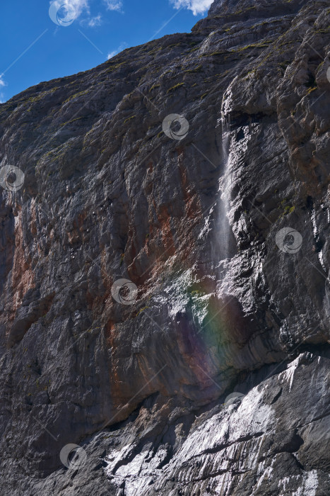 Скачать отвесная скала и водопад с радугой на фоне неба фотосток Ozero