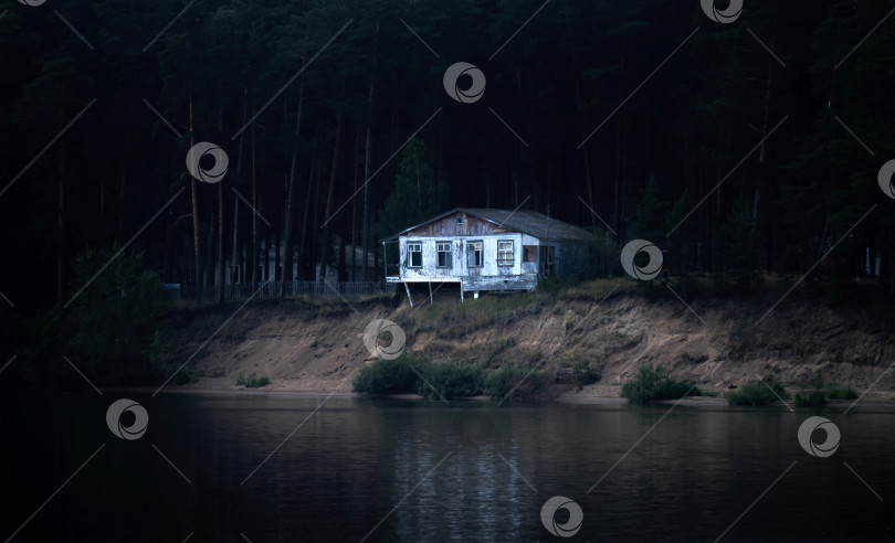 Скачать заброшенный полуразрушенный дом на темном лесистом берегу почти обрушивается фотосток Ozero