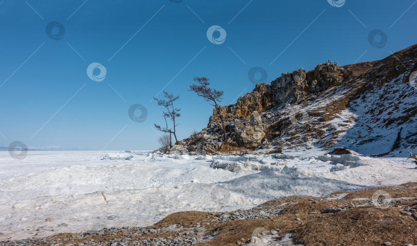 Скачать Замерзшее озеро покрыто снегом. Скалистые берега покрыты льдом. фотосток Ozero