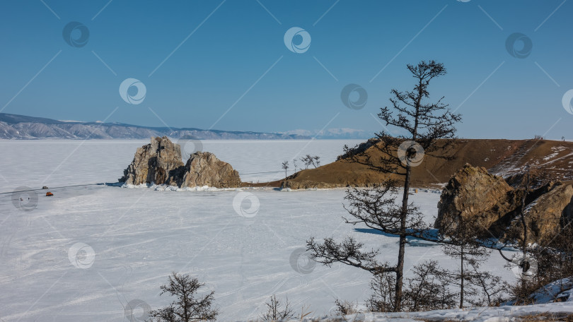 Скачать Двуглавая скала, лишенная растительности, возвышается над замерзшим озером. фотосток Ozero