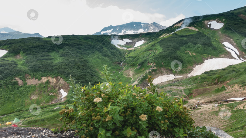 Скачать На склонах гор есть зеленая растительность, участки снега. фотосток Ozero