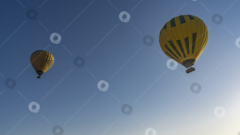 Скачать Ярко-желтые воздушные шары парят в голубом небе. фотосток Ozero
