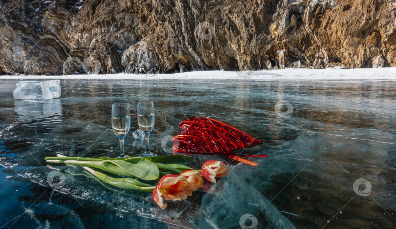 Скачать На прозрачно-голубом льду замерзшего озера стоят два бокала с шампанским, яркие тюльпаны фотосток Ozero