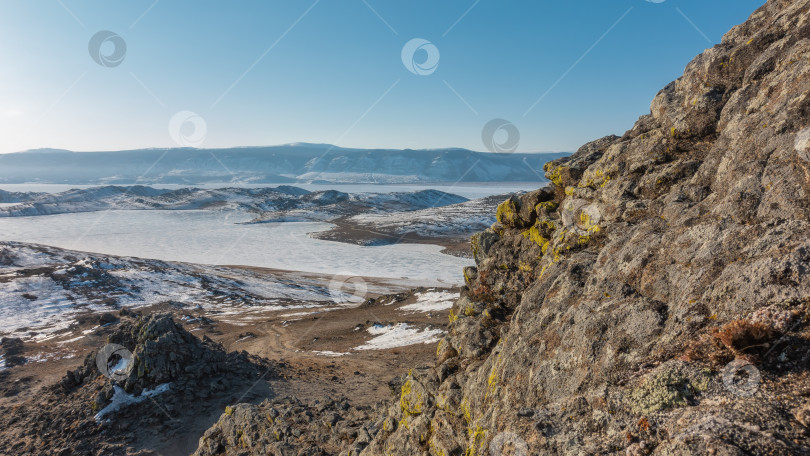 Скачать Замерзшее озеро окружено заснеженными холмами. фотосток Ozero