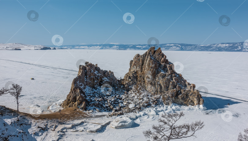 Скачать Живописная двуглавая гранитная скала возвышается над замерзшим озером. фотосток Ozero