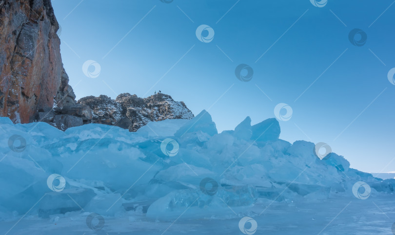 Скачать Глыба голубого льда возвышается у подножия утеса на замерзшем озере. фотосток Ozero