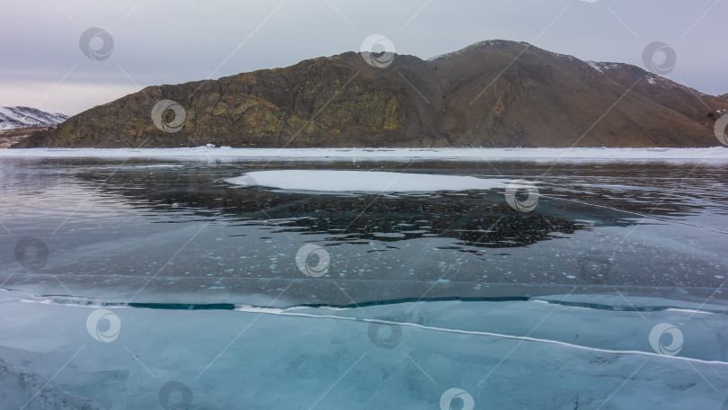 Скачать На гладком, блестящем льду замерзшего озера видны трещины и пузырьки метанового газа. фотосток Ozero