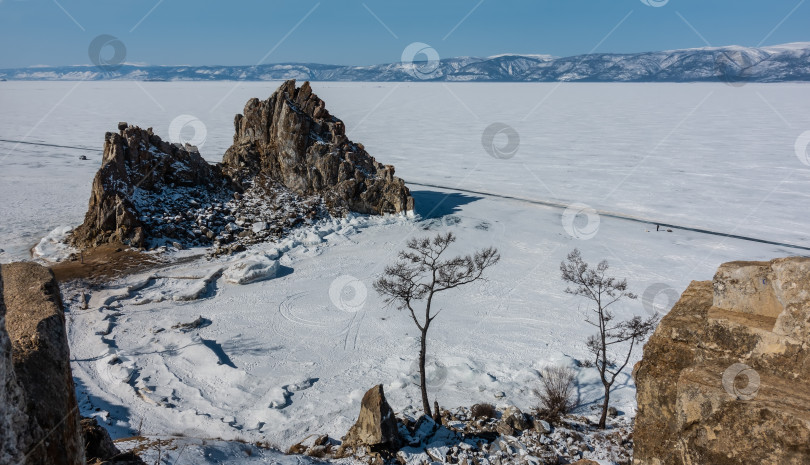 Скачать Живописная гранитная двуглавая скала возвышается над замерзшим озером. фотосток Ozero