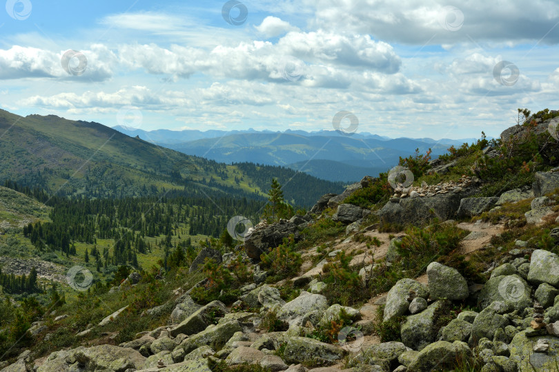 Скачать Пологий склон горы с россыпью крупных камней, откуда открывается вид на живописную горную долину в пасмурный летний день. фотосток Ozero