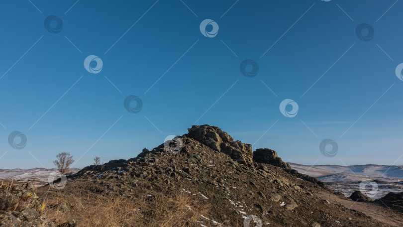 Скачать Скалистый холм на фоне ясного голубого неба. фотосток Ozero