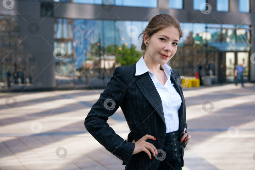 Скачать молодая красивая девушка в пиджаке и белой рубашке позирует на фоне офисного здания в солнечный день фотосток Ozero
