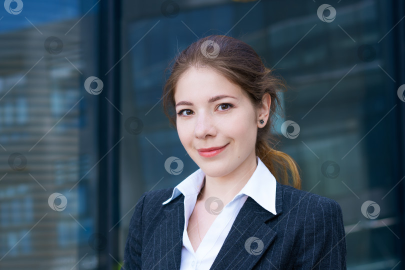Скачать молодая красивая девушка в пиджаке и белой рубашке позирует на фоне офисного здания в солнечный день фотосток Ozero