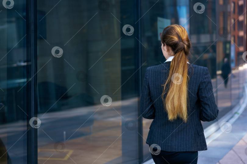 Скачать Деловая женщина в костюме проходит мимо офисного здания фотосток Ozero