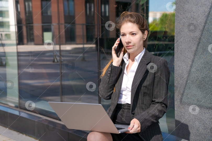Скачать Деловая женщина, работающая на улице. Молодая женщина сидит на скамейке с ноутбуком фотосток Ozero
