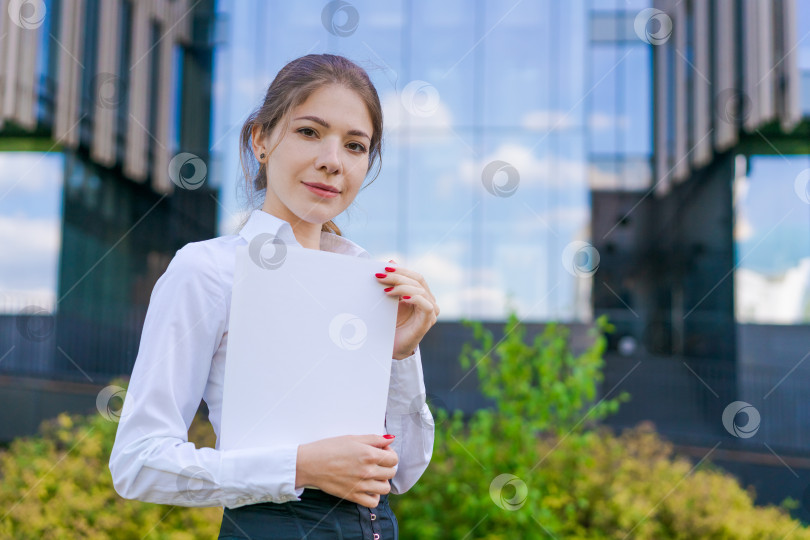 Скачать Элегантная кавказская деловая женщина в официальной одежде держит в руках бумажные документы фотосток Ozero