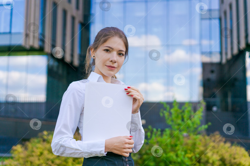 Скачать Молодая деловая женщина с бумагами в деловой одежде на городской улице на фоне фотосток Ozero