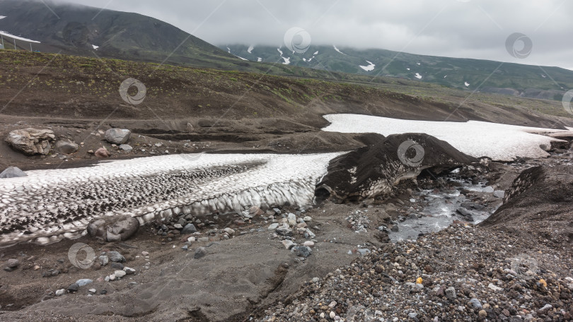 Скачать На каменистой почве горного склона лежит слой растаявшего снега. фотосток Ozero