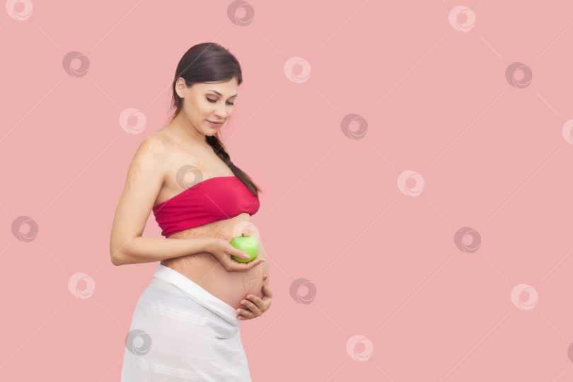 Скачать молодая беременная женщина держит в руках зеленое яблоко фотосток Ozero