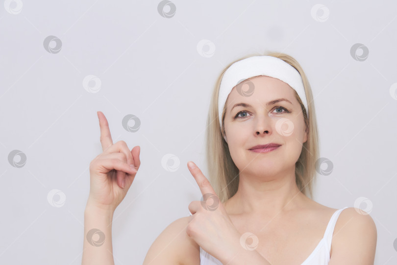 Скачать женщина средних лет с лентой для волос во время косметических процедур указывает на фотосток Ozero