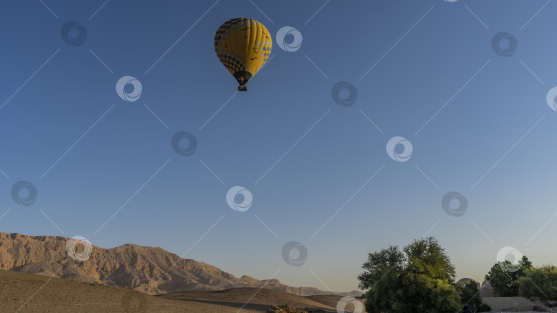 Скачать В голубом небе летит ярко-желтый воздушный шар. фотосток Ozero