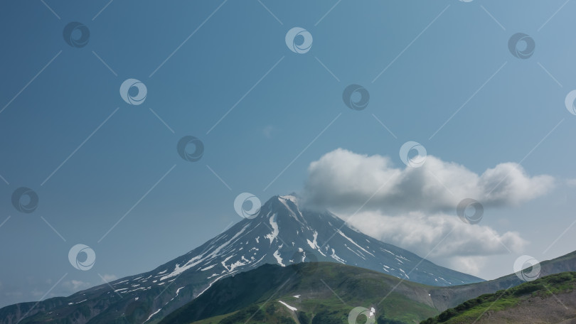 Скачать Живописный конусообразный вулкан с заснеженными склонами на фоне голубого неба. фотосток Ozero