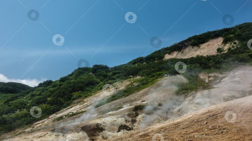 Скачать Дым и пар от фумарол поднимаются над горными склонами. фотосток Ozero