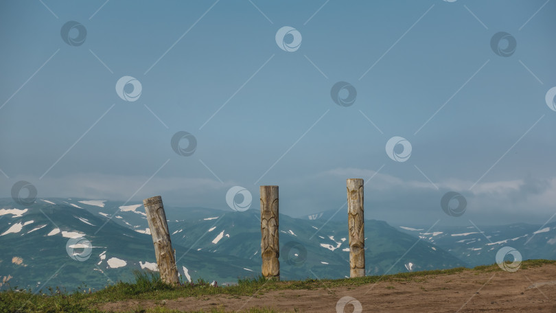 Скачать На склоне холма стоят старые деревянные тотемные столбы. фотосток Ozero