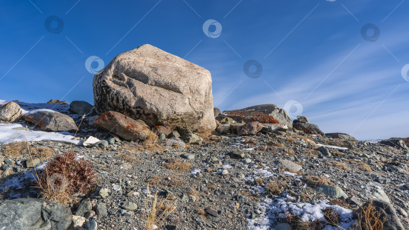 Скачать На склоне холма видна сухая трава, лишайники на камнях, снег на земле. фотосток Ozero