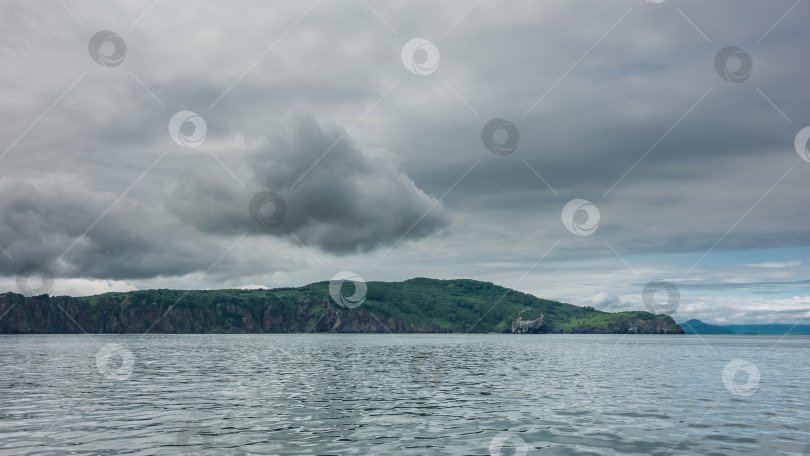 Скачать Холмистое зеленое побережье Камчатки на фоне облачного неба. фотосток Ozero