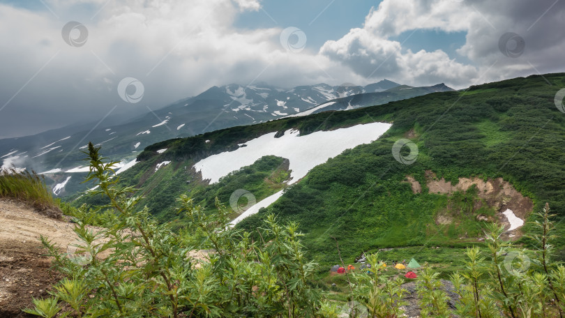 Скачать Зеленые холмы и заснеженные вершины гор на фоне голубого неба и облаков. фотосток Ozero