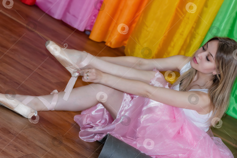 Скачать Очаровательная юная балерина надевает пуанты с лентами фотосток Ozero