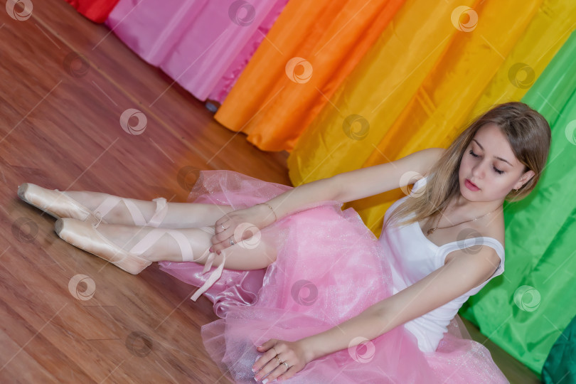 Скачать Очаровательная юная балерина надевает пуанты с лентами фотосток Ozero