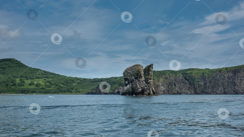 Скачать Живописный утес и зеленое холмистое побережье Камчатки фотосток Ozero