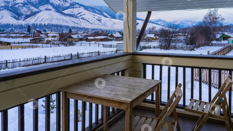 Скачать На балконе туристической базы есть деревянный стол и складные стулья. фотосток Ozero
