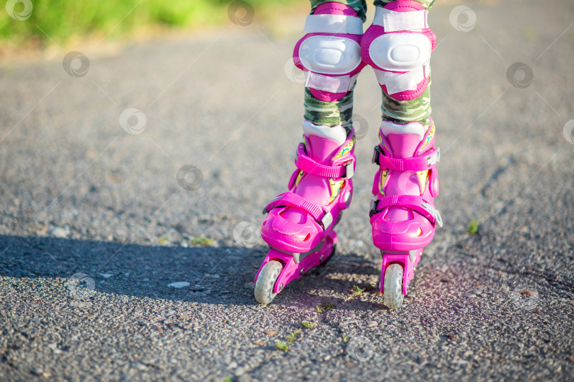 Скачать Детские ножки в розовых детских роликах крупным планом. Роликовые коньки для занятий спортом на открытом воздухе фотосток Ozero