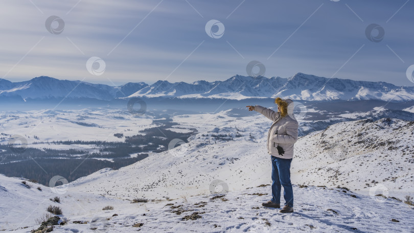 Скачать Мужчина в пуховике стоит на заснеженном высокогорном плато. фотосток Ozero