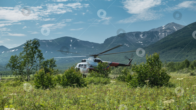 Скачать Вертолет стоит на посадочной площадке на зеленом альпийском лугу. фотосток Ozero