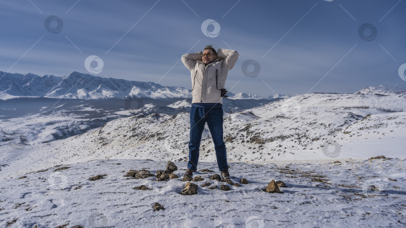 Скачать Мужчина в пуховике стоит на заснеженном высокогорном плато фотосток Ozero