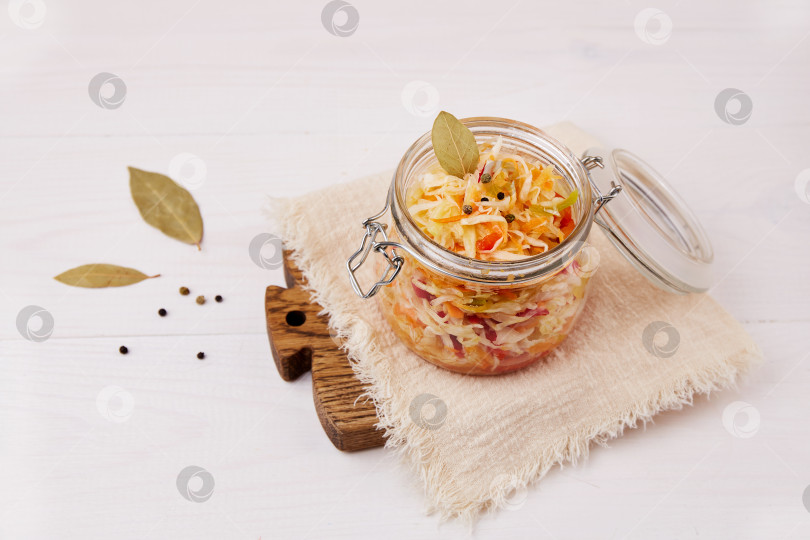 Скачать Домашняя квашеная капуста. Салат из шинкованной капусты с морковью и перцем в банке на белом деревянном фоне. фотосток Ozero