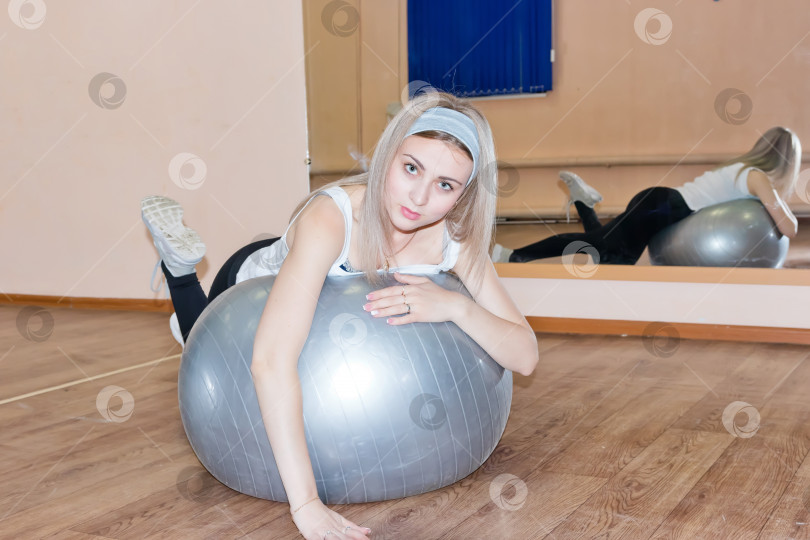 Скачать Грациозная молодая девушка делает фитнес-упражнения на гимнастическом мяче фотосток Ozero