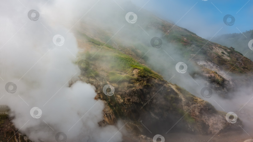 Скачать Облака пара из горячих источников окутывают горные склоны. фотосток Ozero