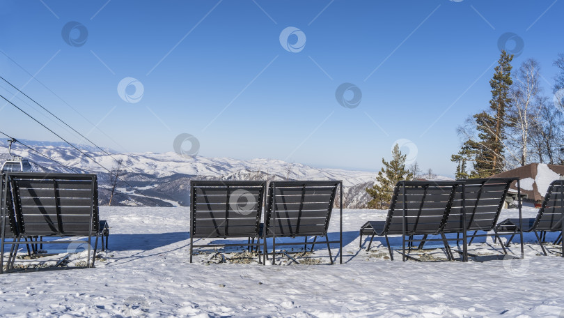 Скачать Деревянные скамейки стоят в ряд на краю заснеженного плато. фотосток Ozero