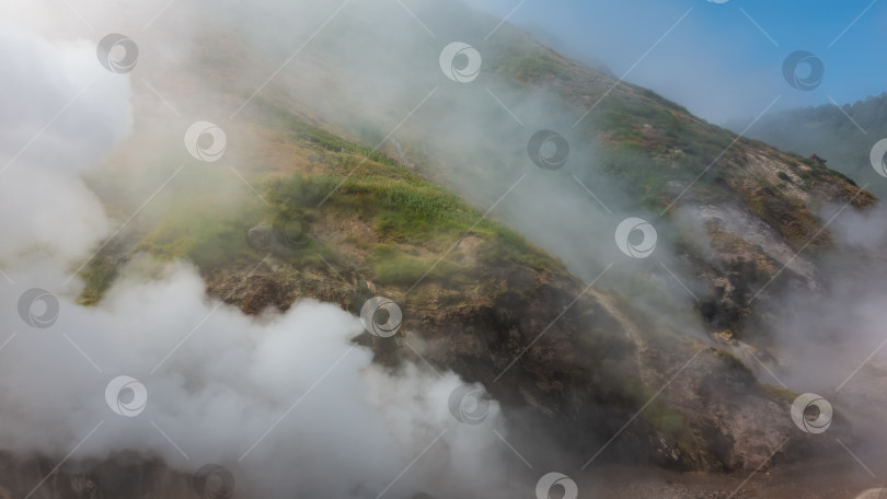 Скачать Густой пар от извергающегося гейзера клубится над склонами холмов. фотосток Ozero