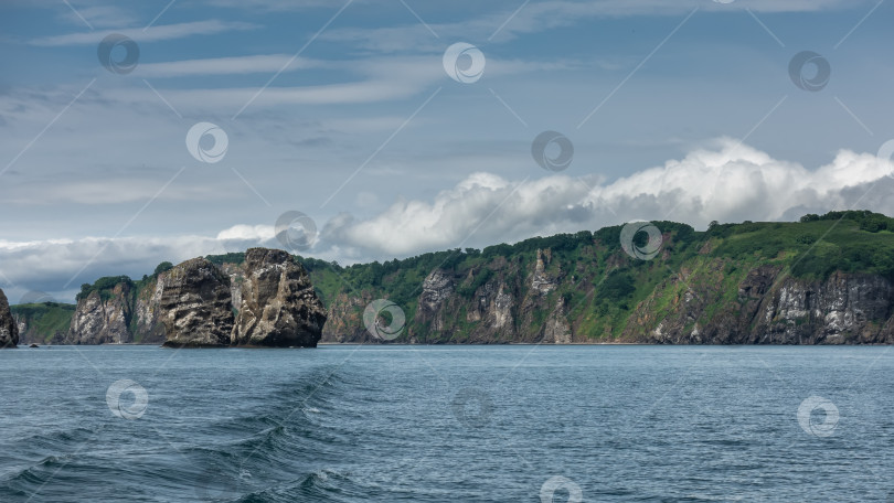 Скачать Живописное побережье Камчатки на фоне голубого неба и облаков. фотосток Ozero